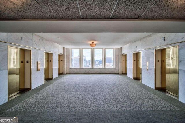 carpeted empty room featuring elevator