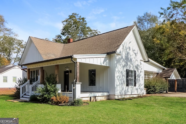 back of house with covered porch and a lawn