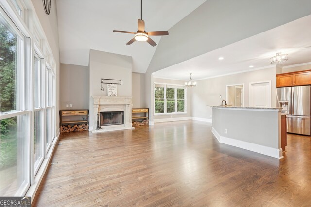 living room featuring high vaulted ceiling, sink, ceiling fan with notable chandelier, hardwood / wood-style flooring, and ornamental molding