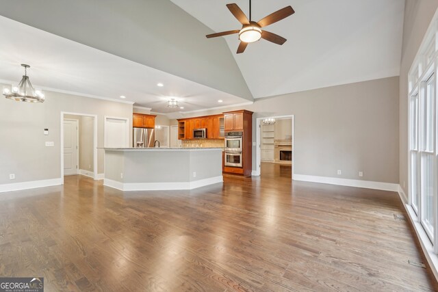 unfurnished living room with dark hardwood / wood-style floors, high vaulted ceiling, sink, and ceiling fan with notable chandelier