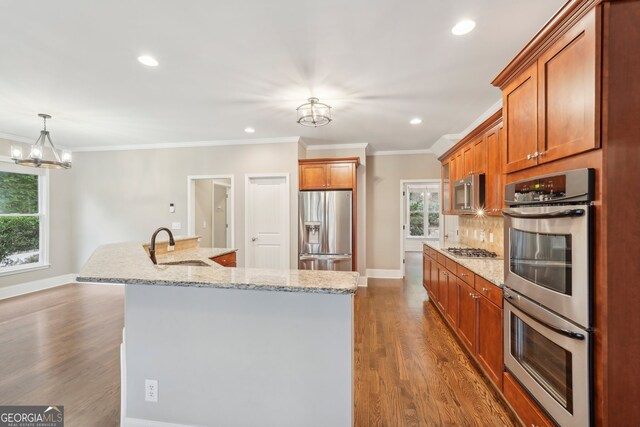 kitchen with light stone counters, a kitchen island with sink, dark hardwood / wood-style floors, sink, and stainless steel appliances