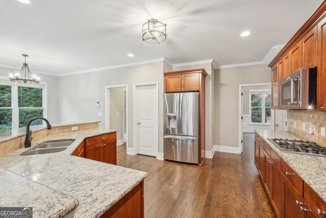 kitchen with decorative backsplash, appliances with stainless steel finishes, a chandelier, pendant lighting, and sink