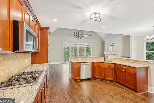 kitchen with decorative backsplash, vaulted ceiling, dark wood-type flooring, sink, and stainless steel appliances