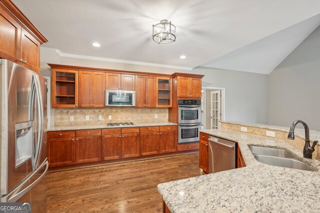 kitchen featuring hardwood / wood-style flooring, sink, light stone countertops, appliances with stainless steel finishes, and tasteful backsplash