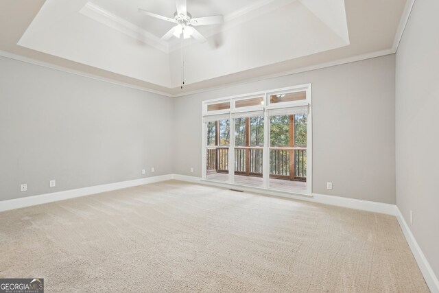 empty room with ceiling fan, ornamental molding, a tray ceiling, and carpet floors