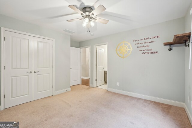 unfurnished bedroom featuring a closet, ceiling fan, ensuite bathroom, and light colored carpet