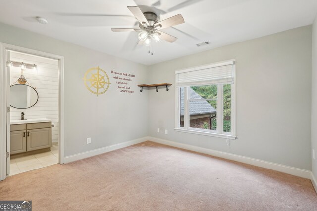 unfurnished bedroom with light colored carpet, connected bathroom, and ceiling fan