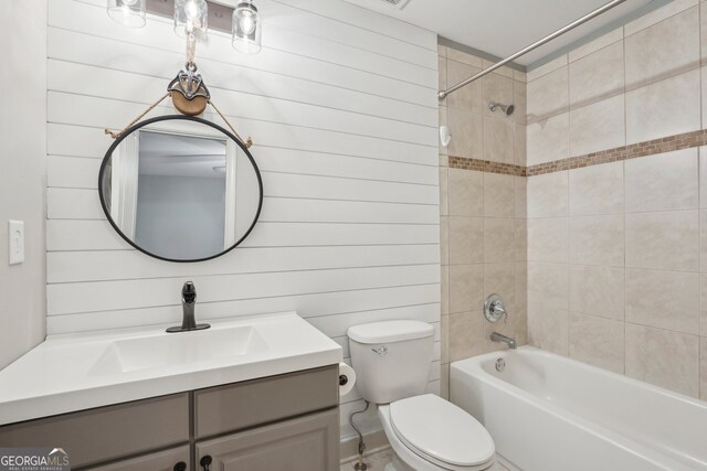 full bathroom with vanity, toilet, tiled shower / bath combo, and wooden walls