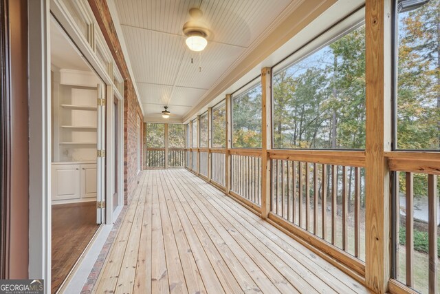 unfurnished sunroom with ceiling fan