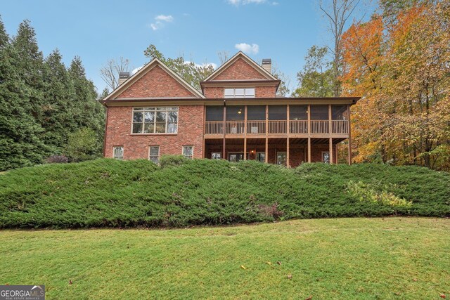 back of property featuring a sunroom and a lawn