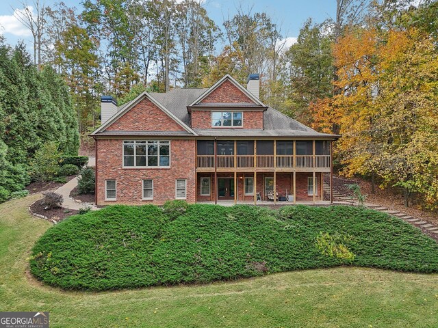 rear view of property with a patio area, a lawn, and a sunroom