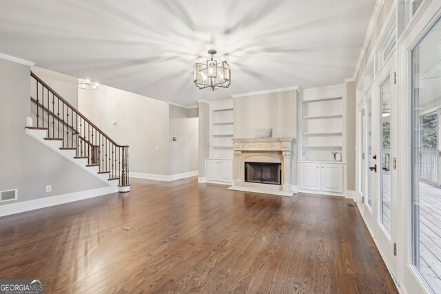 unfurnished living room with a chandelier, dark hardwood / wood-style floors, built in features, crown molding, and french doors