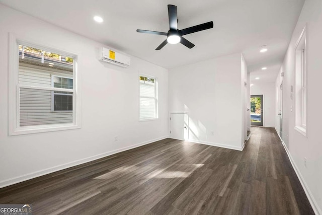 spare room featuring a wall mounted AC, a healthy amount of sunlight, dark hardwood / wood-style floors, and ceiling fan