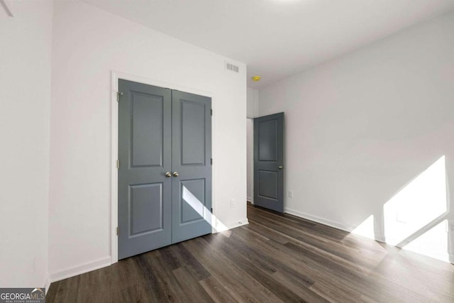 unfurnished bedroom featuring dark hardwood / wood-style flooring and a closet