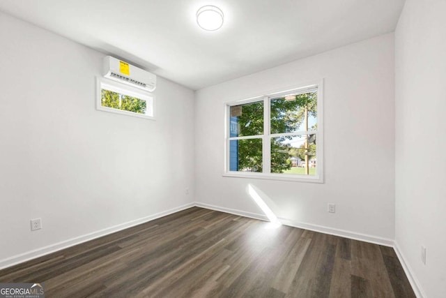 empty room with an AC wall unit, a wealth of natural light, and dark hardwood / wood-style floors