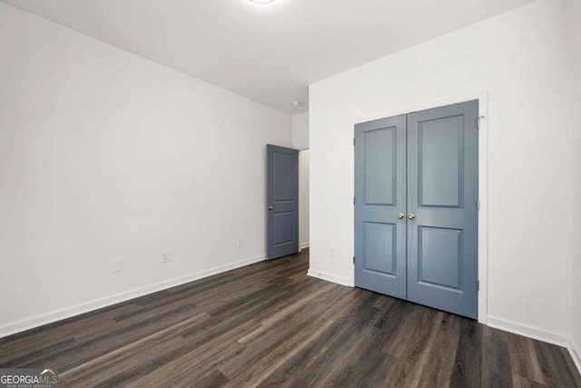 unfurnished bedroom with dark hardwood / wood-style flooring and a closet