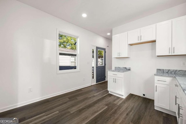 kitchen featuring dark wood-type flooring, light stone countertops, and white cabinets