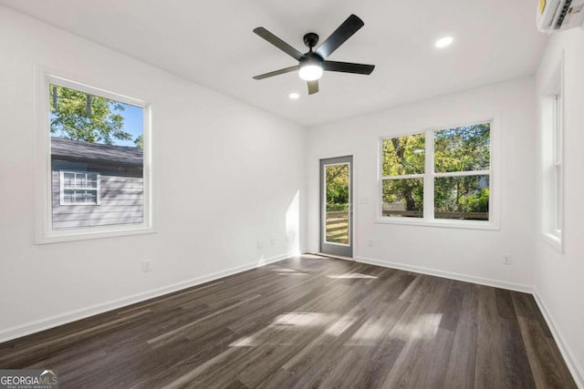 spare room featuring dark wood-type flooring, ceiling fan, and a wall mounted air conditioner