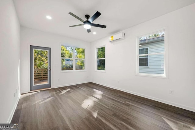 empty room with dark wood-type flooring, a wall mounted air conditioner, and ceiling fan