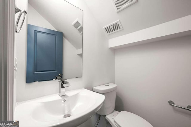 bathroom with sink, toilet, and vaulted ceiling