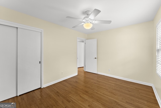 unfurnished bedroom featuring a closet, multiple windows, hardwood / wood-style flooring, and ceiling fan