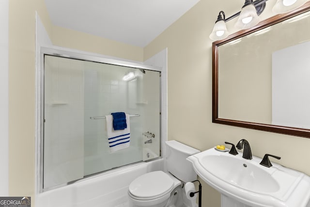 full bathroom featuring toilet, combined bath / shower with glass door, and sink