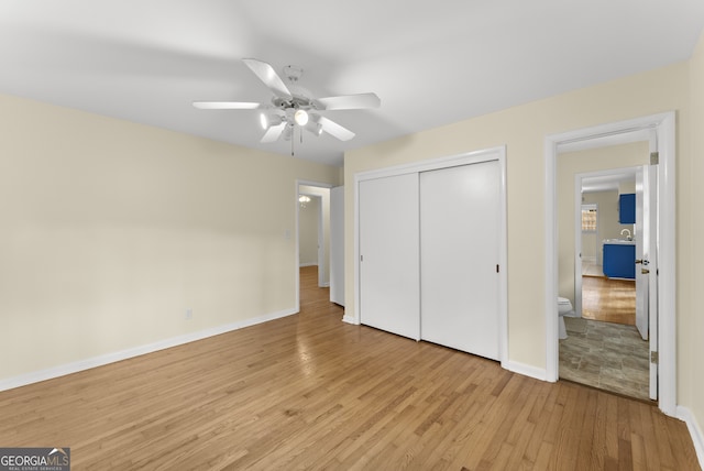 unfurnished bedroom featuring light hardwood / wood-style floors, a closet, ensuite bathroom, and ceiling fan