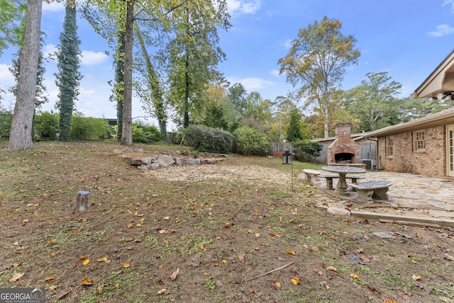 view of yard featuring a patio, an outdoor stone fireplace, and central air condition unit