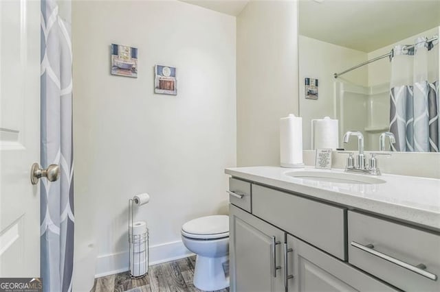 bathroom featuring toilet, walk in shower, vanity, and wood-type flooring