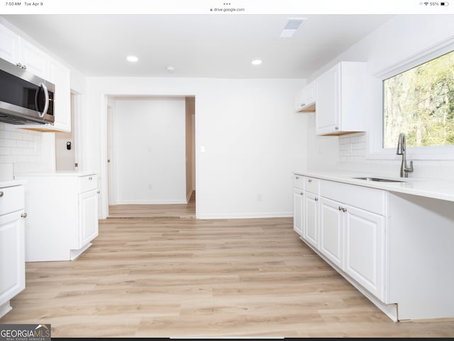 kitchen with light hardwood / wood-style flooring, white cabinetry, and backsplash