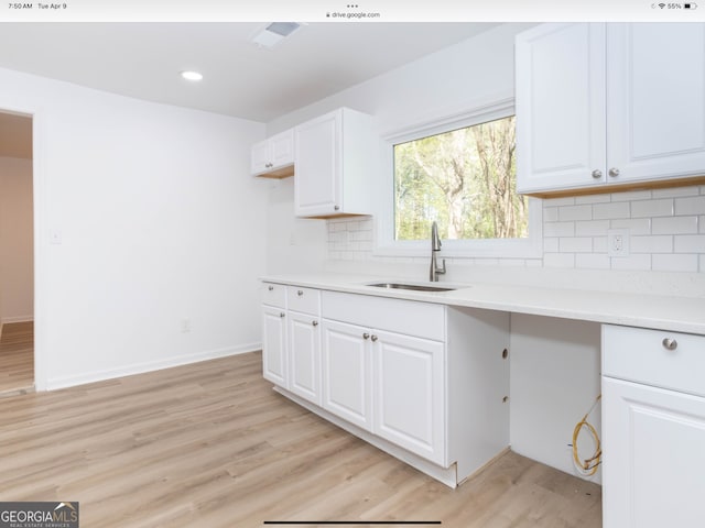 kitchen featuring white cabinetry, light hardwood / wood-style floors, sink, and backsplash