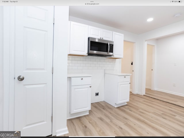 kitchen with white cabinetry, light hardwood / wood-style floors, and backsplash