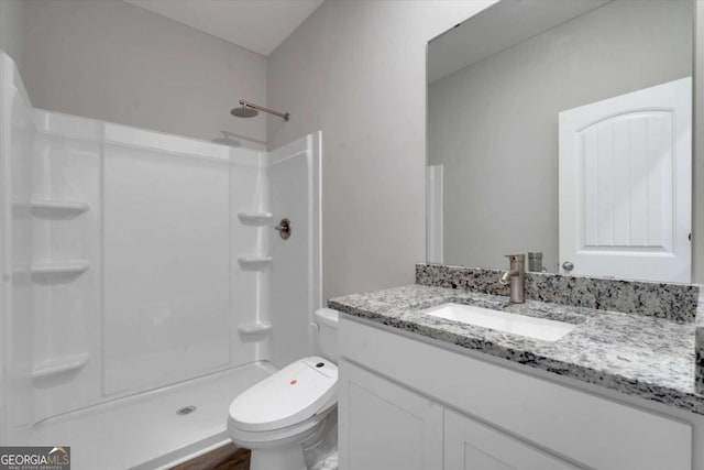 bathroom featuring a shower, vanity, and toilet