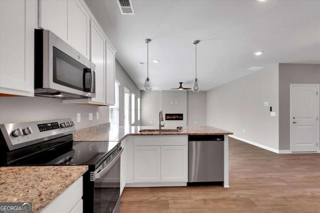 kitchen with stainless steel appliances, sink, decorative light fixtures, light hardwood / wood-style floors, and white cabinetry