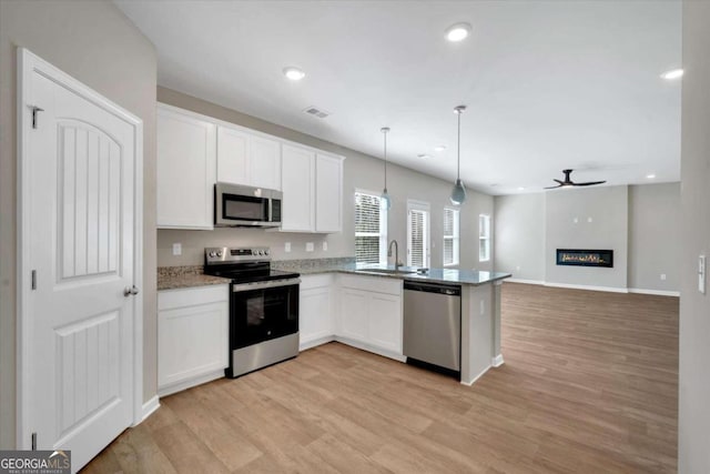 kitchen featuring white cabinets, appliances with stainless steel finishes, decorative light fixtures, and kitchen peninsula