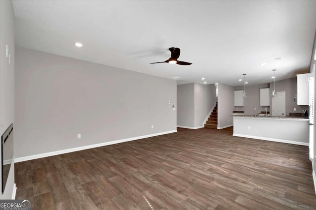 unfurnished living room with ceiling fan and dark hardwood / wood-style flooring