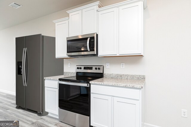 kitchen with appliances with stainless steel finishes, light wood-type flooring, and white cabinetry