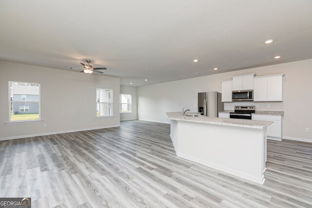 kitchen featuring a kitchen island with sink, sink, light wood-type flooring, white cabinetry, and appliances with stainless steel finishes