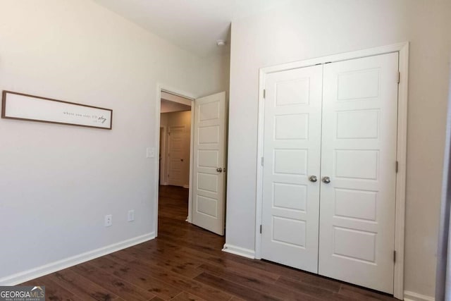 unfurnished bedroom with dark wood-type flooring and a closet