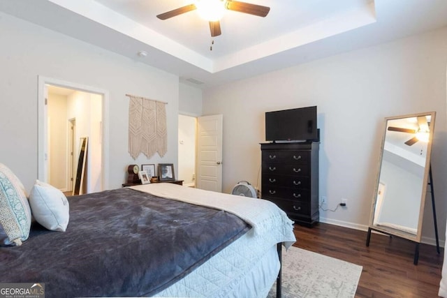 bedroom featuring a tray ceiling, ceiling fan, and dark wood-type flooring