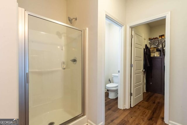 bathroom featuring hardwood / wood-style flooring, toilet, and a shower with door