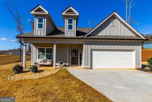 view of front of home featuring covered porch, a front yard, and a garage