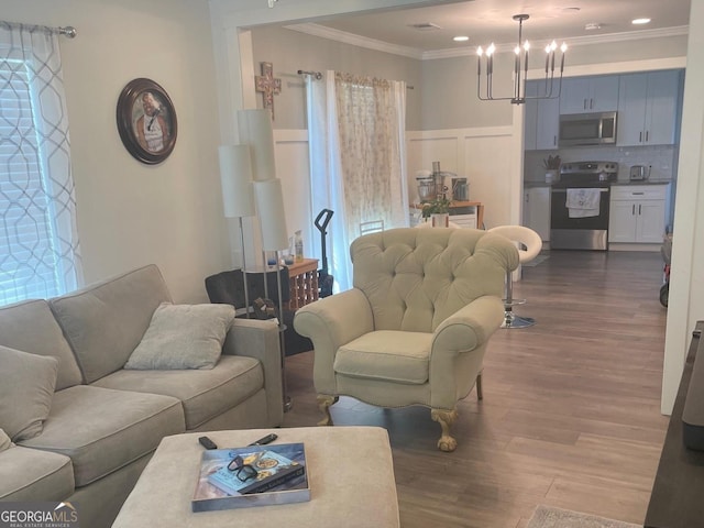 living room featuring dark wood-type flooring, crown molding, a notable chandelier, and a healthy amount of sunlight