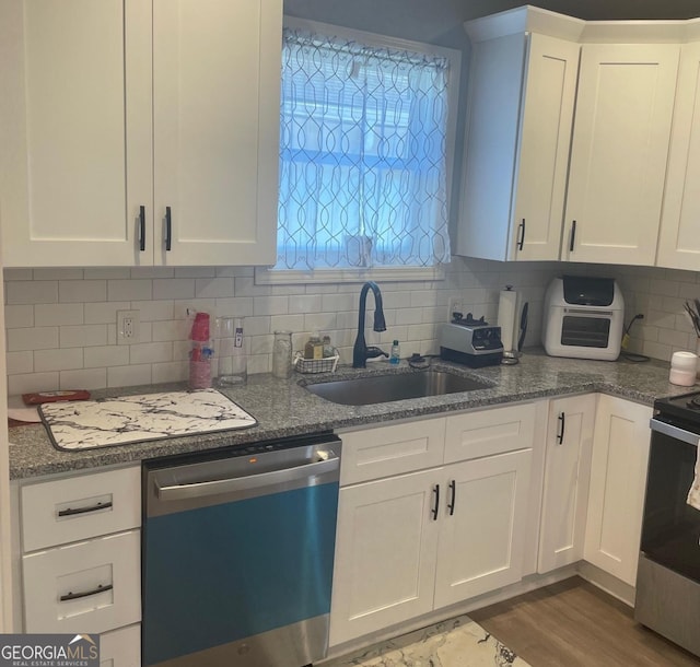 kitchen featuring appliances with stainless steel finishes, sink, white cabinets, decorative backsplash, and dark hardwood / wood-style floors