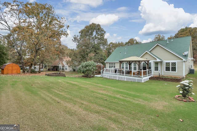 back of property with central AC unit, a lawn, a gazebo, and a storage shed