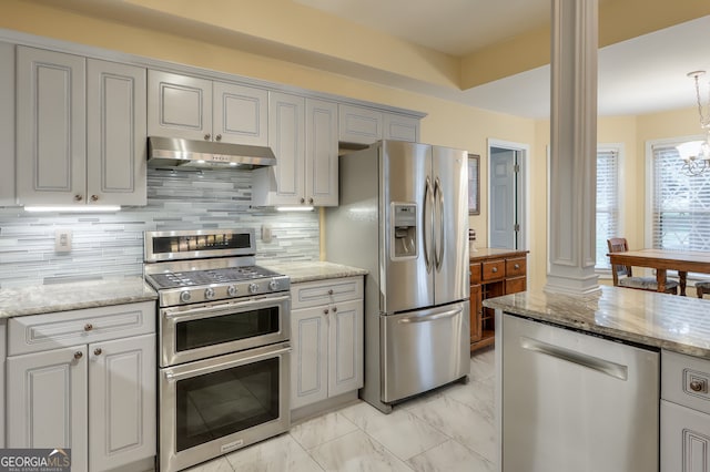 kitchen with light stone counters, an inviting chandelier, decorative backsplash, decorative columns, and appliances with stainless steel finishes