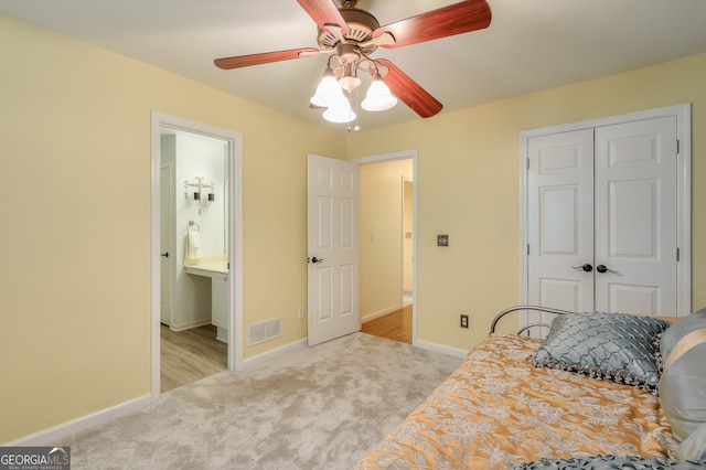 carpeted bedroom featuring ensuite bath, ceiling fan, and a closet