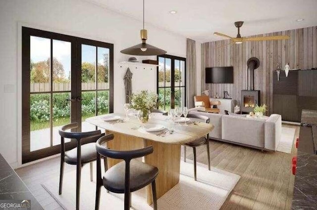 dining room featuring light hardwood / wood-style flooring, french doors, a wood stove, and ceiling fan