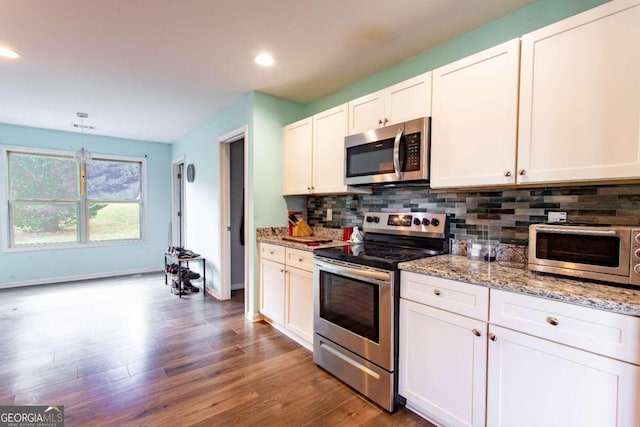 kitchen with hanging light fixtures, stainless steel appliances, wood-type flooring, white cabinetry, and light stone counters