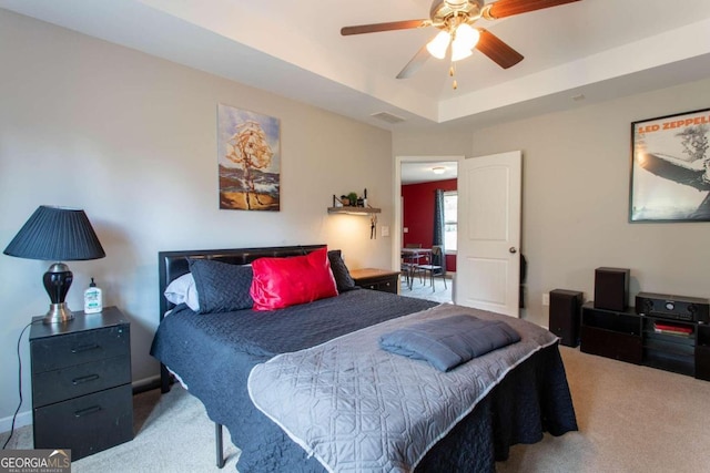 carpeted bedroom with a tray ceiling and ceiling fan